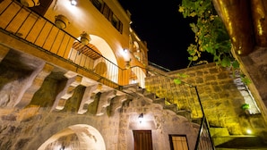 A stone staircase with a wooden door at the bottom, leading to a building with a balcony. - Maya Cave Hotel (Nevsehir)