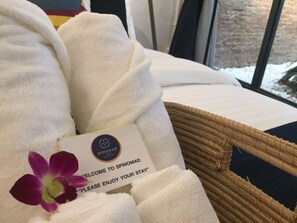 A bed with white linens and a welcome card for Spinomad. - Spinomad Hostel (Chiang Rai)