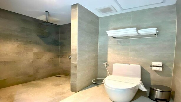 Une salle de bain moderne avec une douche à l’italienne, des toilettes et une poubelle.