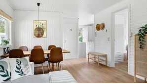 Un coin repas avec une table et des chaises en bois, un luminaire suspendu et une œuvre d’art encadrée au mur.