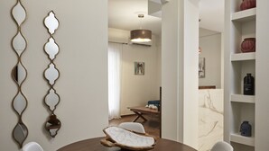 A dining area with a round wooden table, white chairs, and a unique wooden serving tray. - Cozy and Bright Apartment in Kolonaki (Athens)