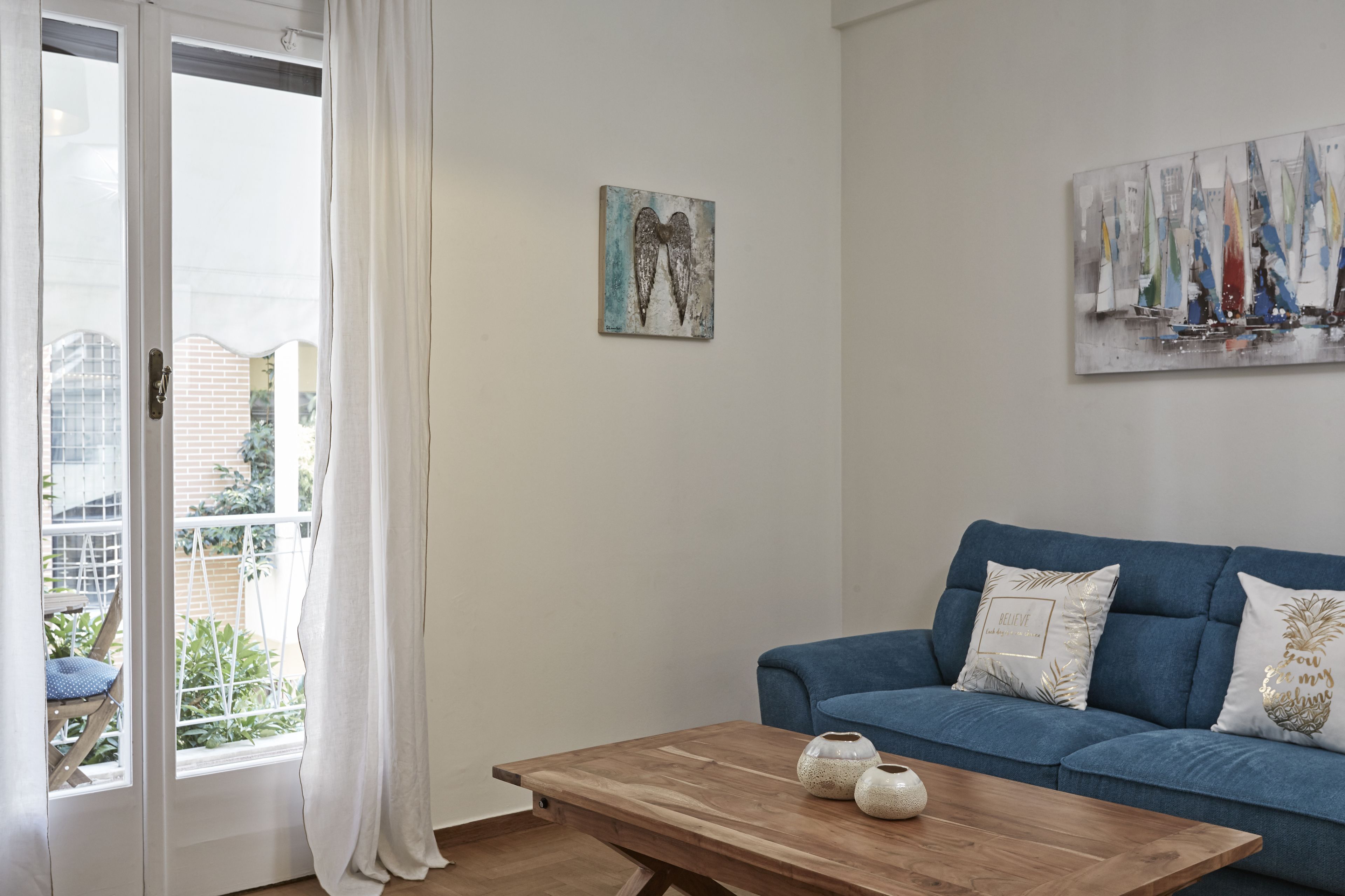 Un salon avec un canapé bleu, une table basse en bois et deux tableaux accrochés au mur.