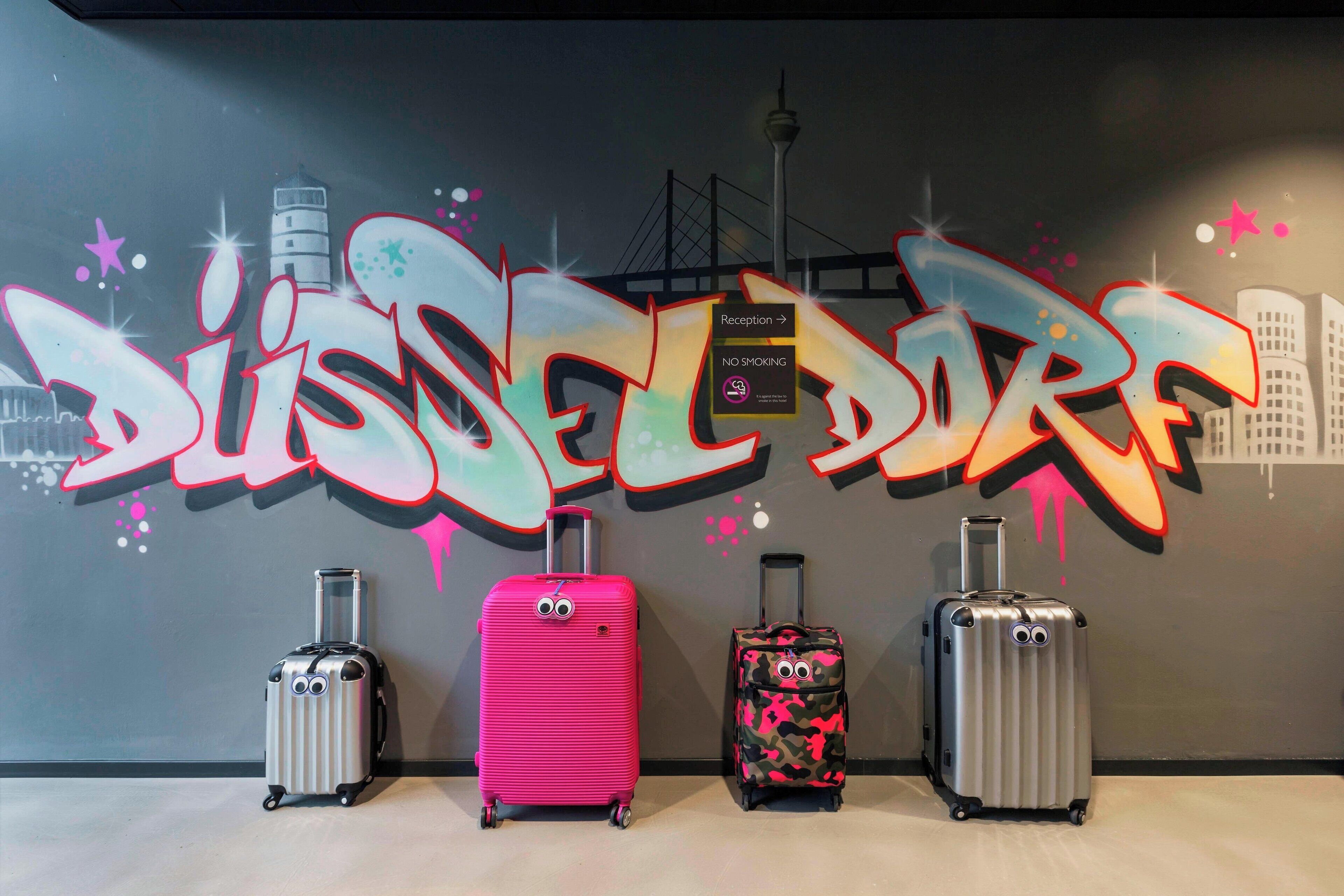 A wall with graffiti art and four suitcases.