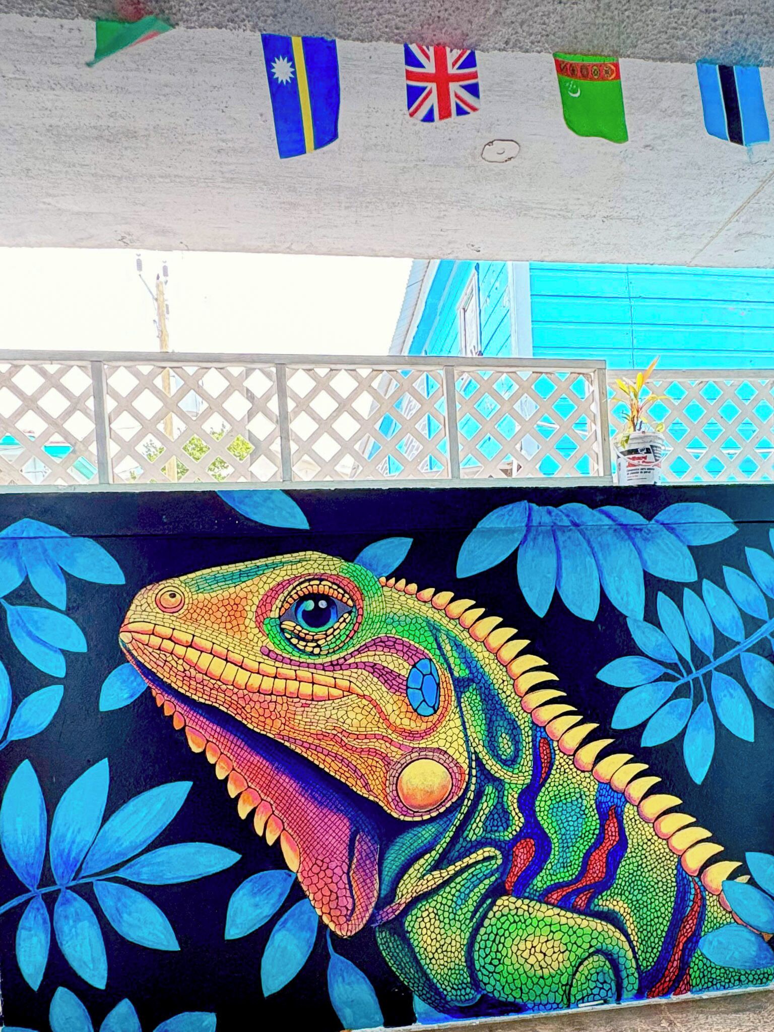 Un mural colorido de una lagartija sobre fondo azul y motivos florales.