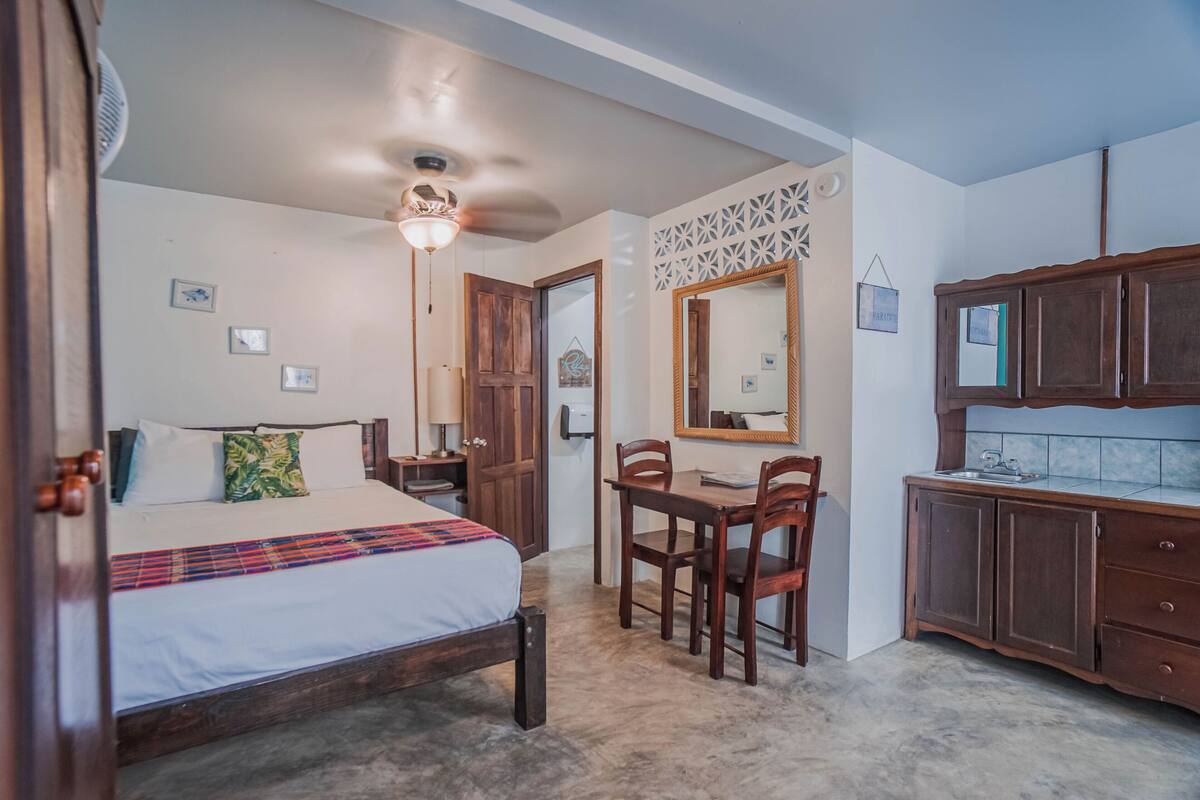 A bedroom with a bed, a desk, and a mirror.