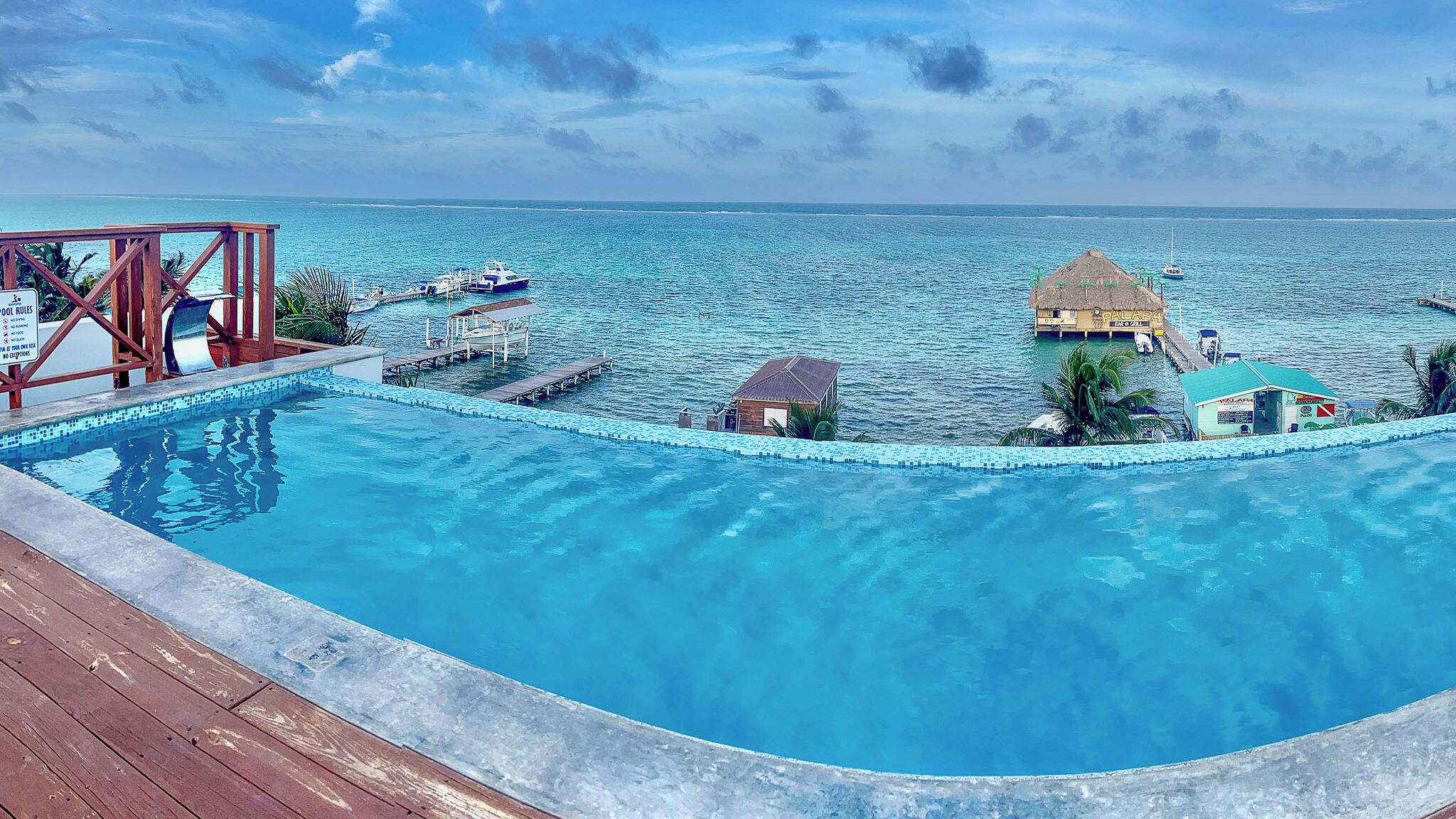 Une piscine dotée d’une terrasse en bois et offrant une vue sur l’océan.