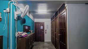 A narrow hallway with wooden lockers, a fan, and a door at the end. - Drift Inn San Pedro (San Pedro)