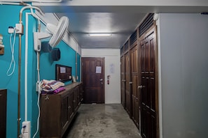 A narrow hallway with wooden lockers, a fan, and a door at the end. - Drift Inn San Pedro (San Pedro)