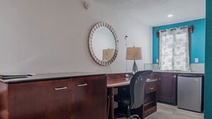A compact office space with a wooden desk, a chair, a small refrigerator, and a mirror on the wall. - Drift Inn San Pedro (San Pedro)