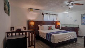A bedroom with a bed, bedside tables, a desk, a ceiling fan, and a small bathroom area. - Drift Inn San Pedro (San Pedro)