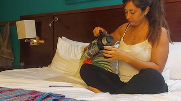 Una persona sentada en una cama con una manta colorida, sosteniendo una cámara.