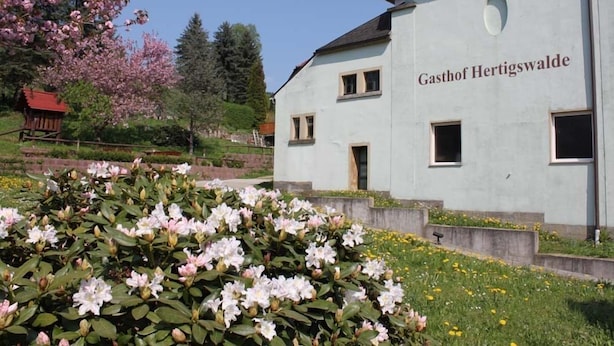 Un bâtiment portant l’inscription « Gasthof Hertigswalde », avec un jardin en premier plan.
