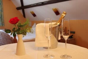 A table with a vase of flowers and two champagne glasses, a bottle of champagne, and a candle holder. - Gasthof Hertigswalde (Sebnitz)