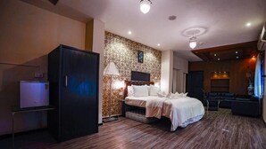 Une chambre d’hôtel avec un lit, une télévision, un réfrigérateur et un mur décoré de motifs.