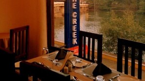 Un restaurant avec vue sur une rivière et, au fond, un bâtiment portant l’inscription « THE CREEK ».