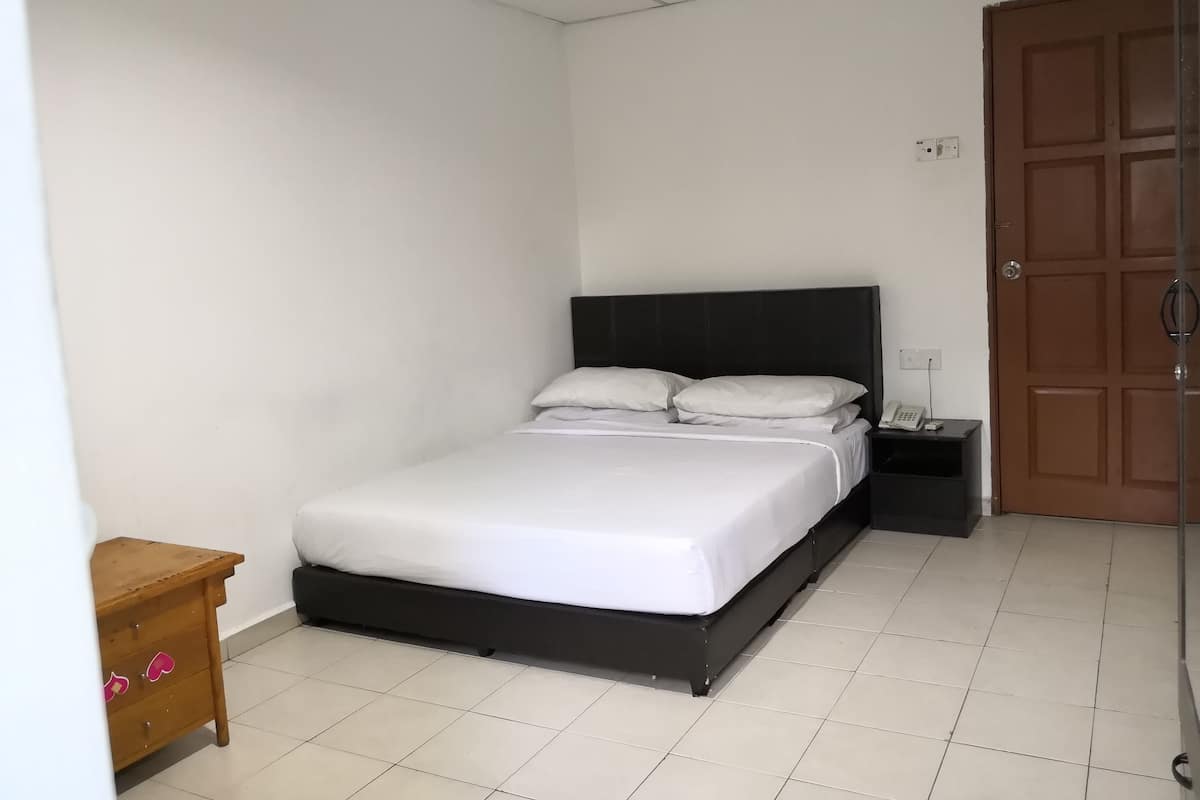 A bedroom with a bed, a nightstand, a wooden dresser, and a door.