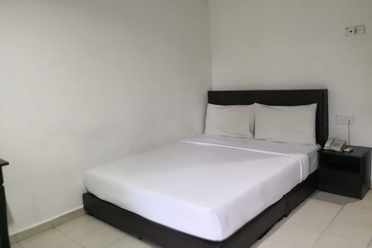 A neatly made bed with white linens, a black headboard, and a bedside table with a telephone.