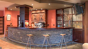A bar area with a stone counter, three stools, and wooden cabinets. - Hotel Cotiella (Campo)