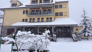 A multi-story building with a snow-covered roof and balconies. - Hotel Cotiella (Campo)