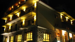 A multi-story hotel with balconies and illuminated windows at night. - Hotel Cotiella (Campo)