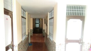 Um corredor com paredes e chão em azulejo, que leva a uma porta com o número 204.