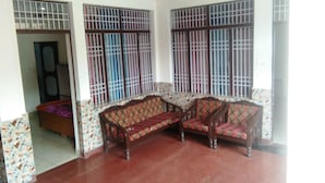 Quarto com sofá, parede estampada e janelas com grades.