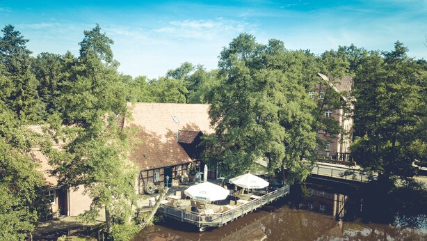 Un bâtiment situé au bord de la rivière, doté d’un quai et entouré d’une végétation dense.