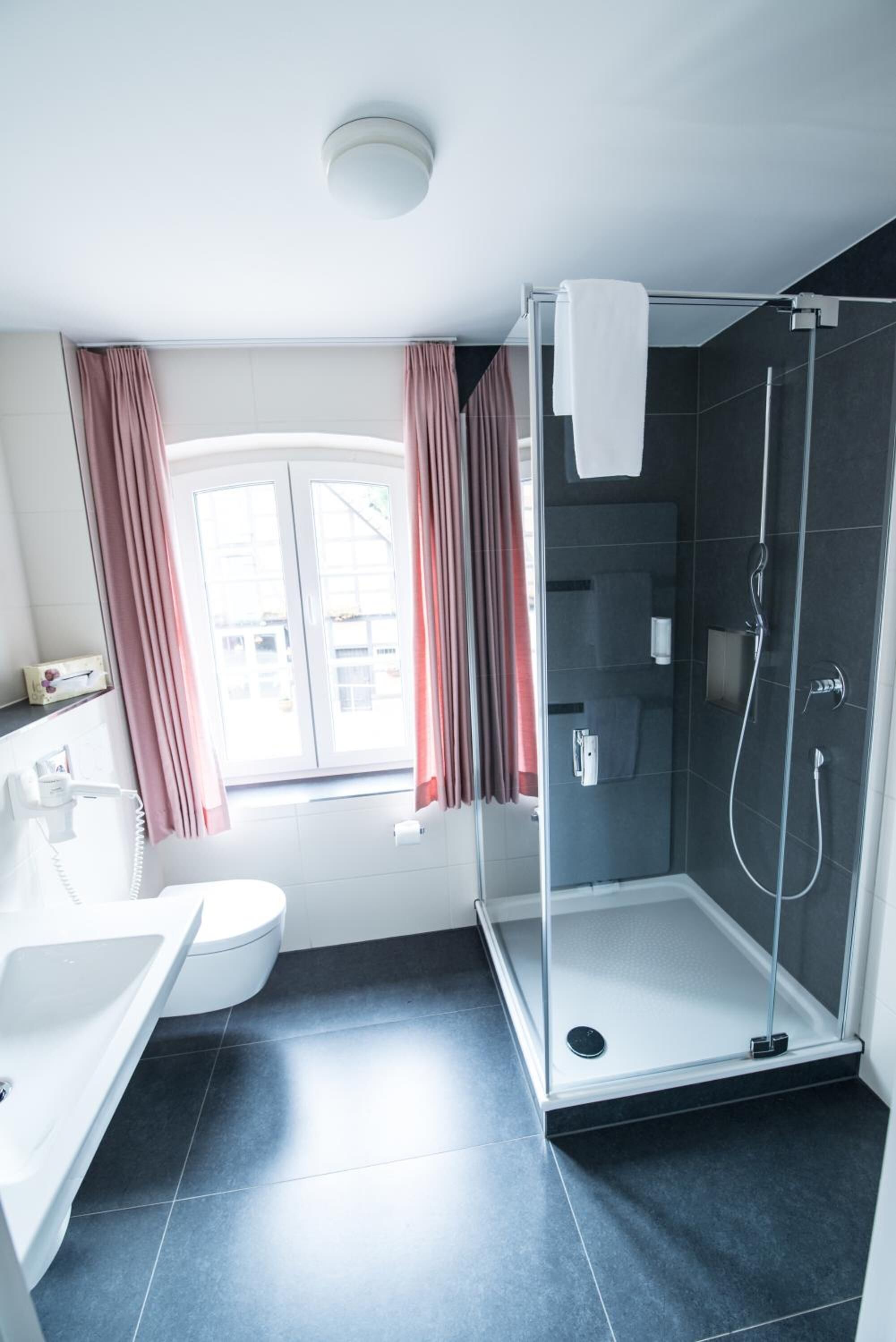 Ein modernes Badezimmer mit einer Duschkabine aus Glas, einer Toilette und einem Waschbecken.