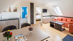 Une chambre d’hôtel moderne dotée d’un coin repas, d’une kitchenette et d’un espace de vie avec un canapé et un téléviseur.