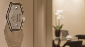 A hexagonal sign with the number 10 on a wall, a glass table with chairs, and a potted plant in the background.