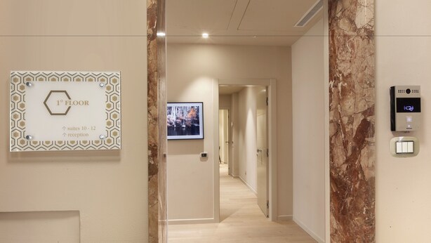 A hotel corridor with a reception sign indicating suites 10-12 and a reception area.