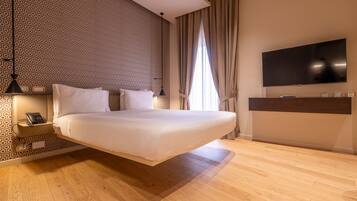 A modern bedroom with a hanging bed, a bedside telephone, a TV mounted on the wall, and a patterned wallpaper.