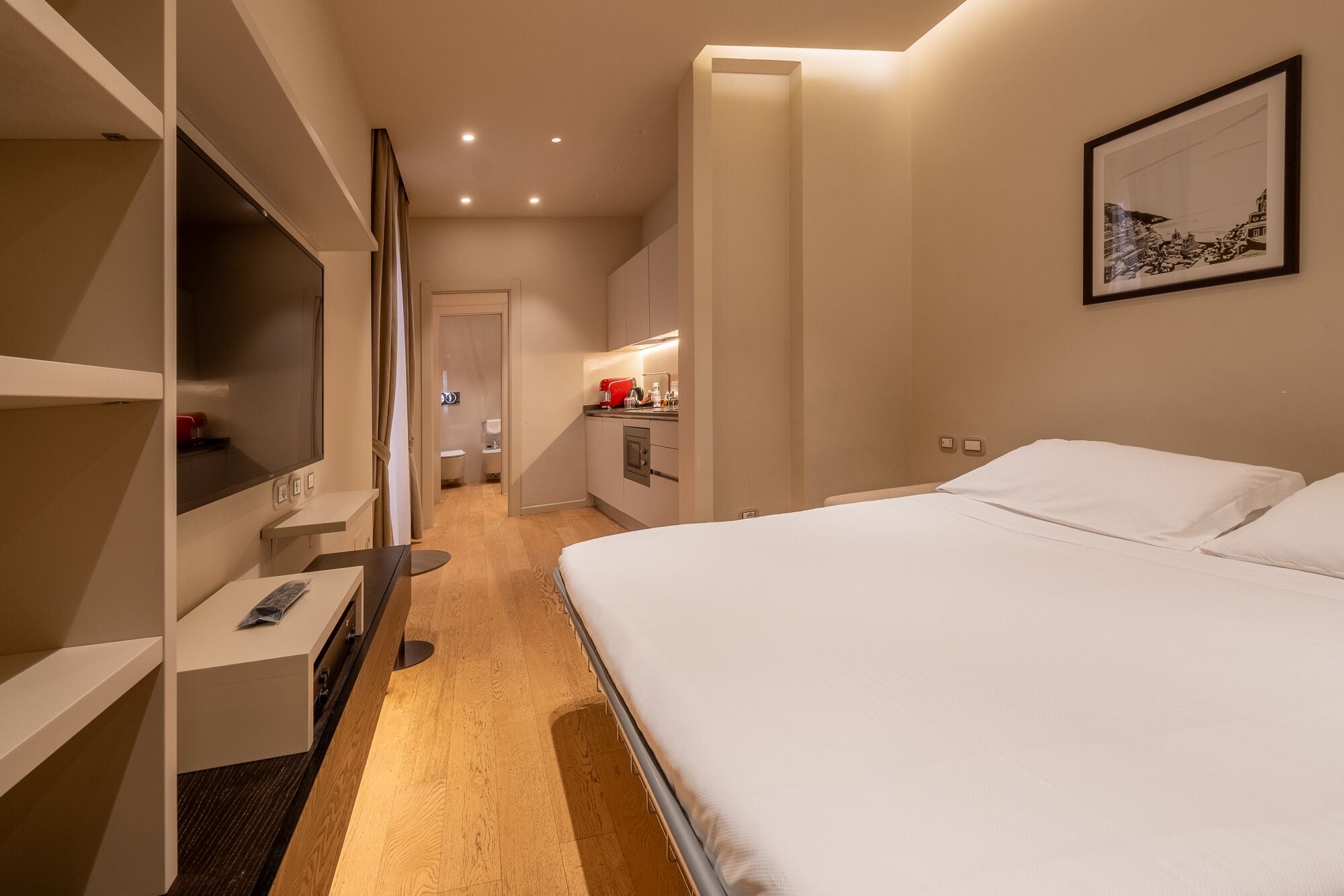 A hotel room with a bed, a desk, a wardrobe, and a bathroom visible through an open door.