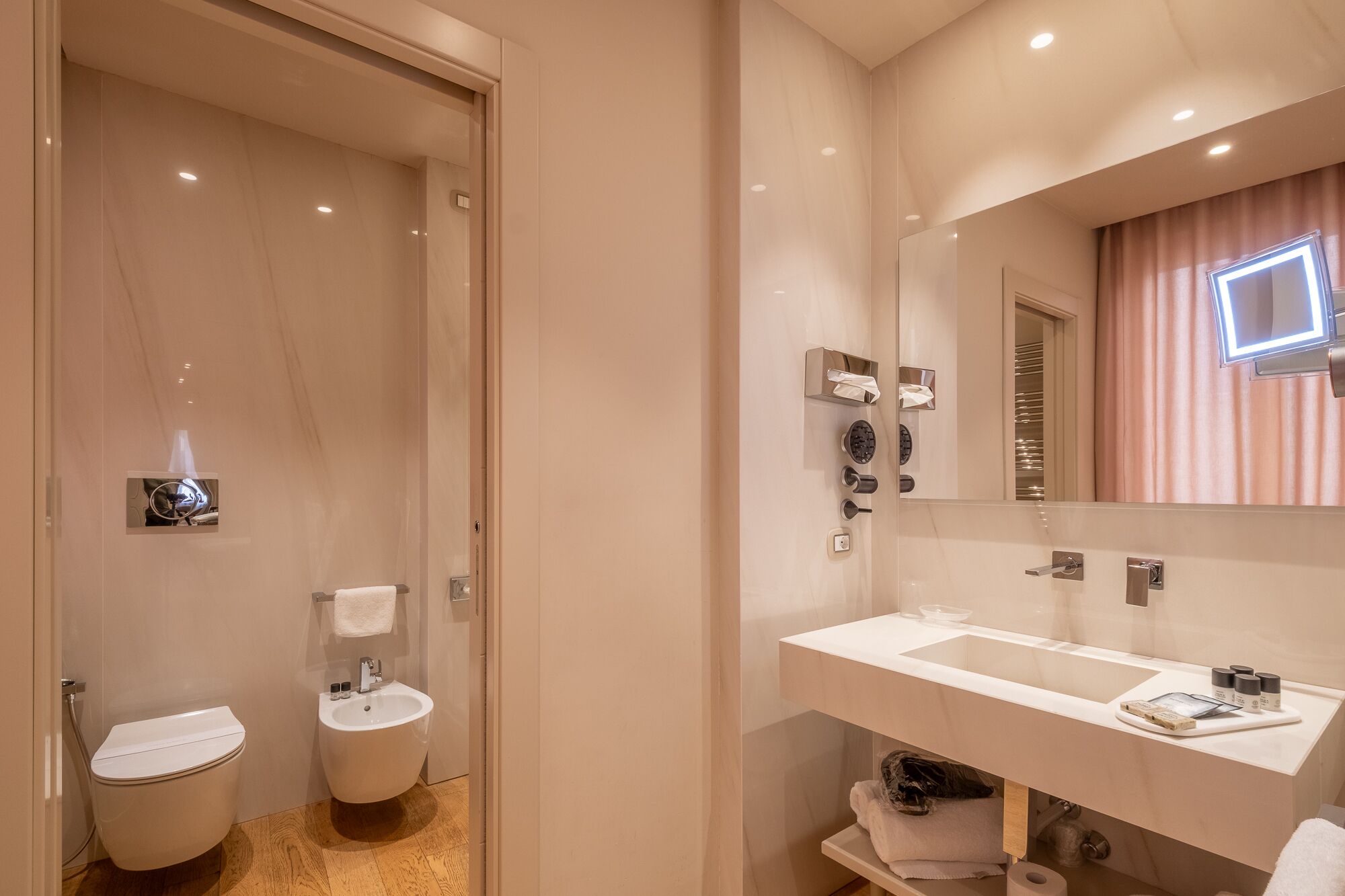 Une salle de bain moderne équipée de toilettes, d’un bidet et d’un meuble-lavabo avec un miroir.