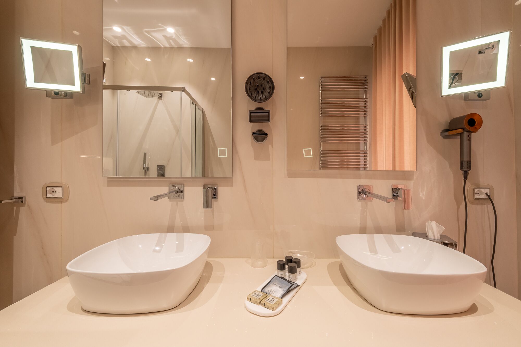 A bathroom with two sinks, a mirror, a towel rack, and a hairdryer.