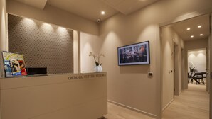 A reception desk with a patterned wall, a framed photo, and a vase with flowers.