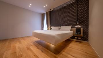 Un dormitorio moderno con una cama grande, suelo de madera, pared estampada y una mesita de noche con lámpara.