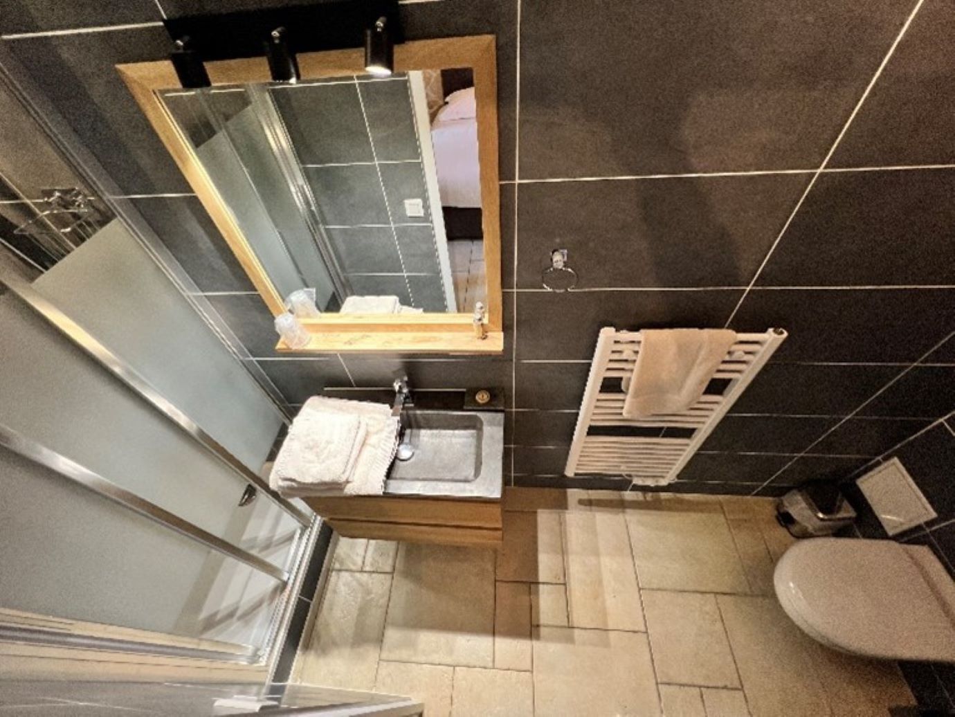 Un baño pequeño con lavamanos, espejo, toallero y retrete.