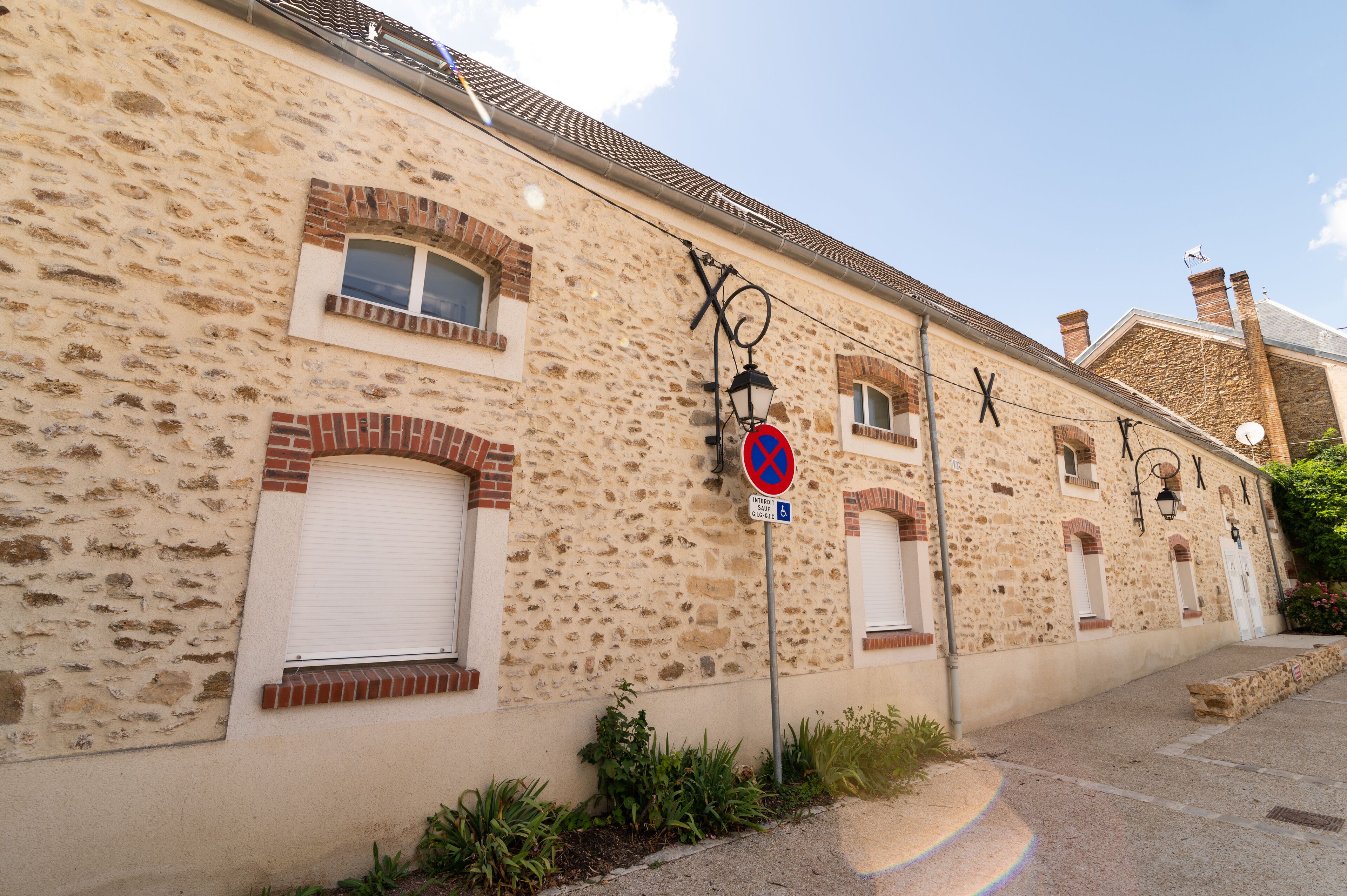 A stone building with a no parking sign, a no entry sign, and a wheelchair accessibility sign.