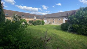 A courtyard with a grassy lawn, surrounded by brick buildings with multiple windows and doors.