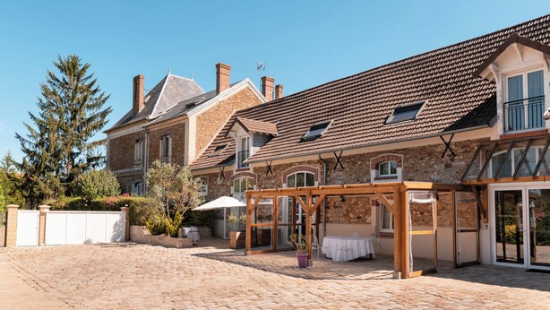 A spacious courtyard with a covered seating area, stone walls, and a large tree.
