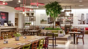 A modern cafe with wooden tables, colorful chairs, and red pendant lights. - IntercityHotel Frankfurt Hauptbahnhof Süd (Frankfurt)