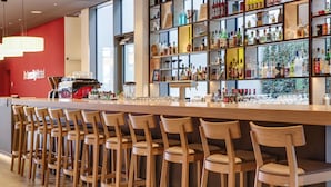 A bar area with wooden chairs and a counter stocked with bottles and glasses. - IntercityHotel Frankfurt Hauptbahnhof Süd (Frankfurt)