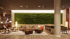 A modern living room with a green wall, a fireplace, and a large column. - IntercityHotel Frankfurt Hauptbahnhof Süd (Frankfurt)