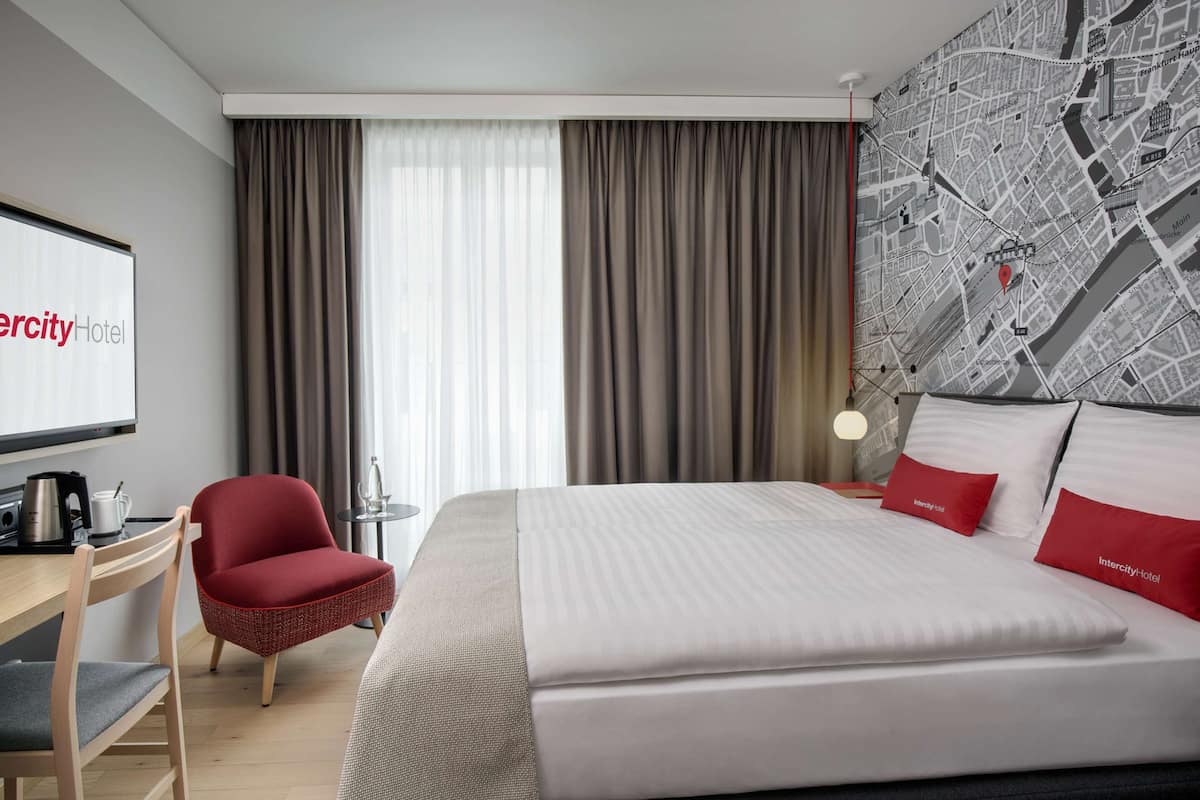Une chambre d’hôtel avec un grand lit, un bureau avec une chaise, une télévision et une carte accrochée au mur.