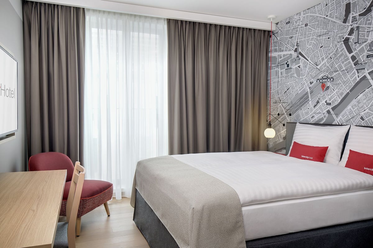 Une chambre d’hôtel avec un lit, un bureau, une chaise et une carte accrochée au mur.