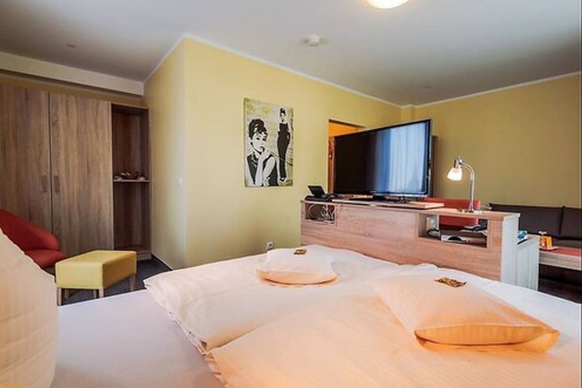 A hotel room with a bed, a TV, a desk, and a chair.