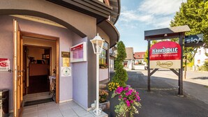 A hotel entrance with a signboard, a door, and a flower planter. - Hotel Restaurant Kasserolle (Siegburg)