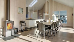 A modern kitchen with a central island, a dining area with a long table and chairs, and a wood-burning stove. - 7 bedroom lovely home in Frederiksværk (Frederiksværk)