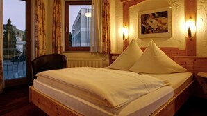 A wooden-framed room with a bed, a chair, a window with curtains, and a wall-mounted light fixture. - Hotel Bruker (Grossbottwar)